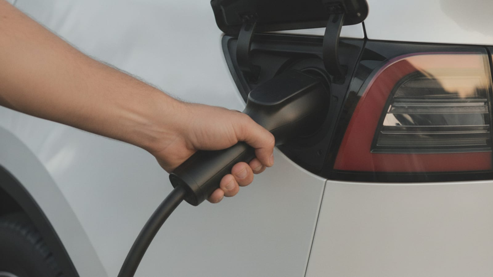 Charge cable locked into an EV port at a public stall, handle still seated